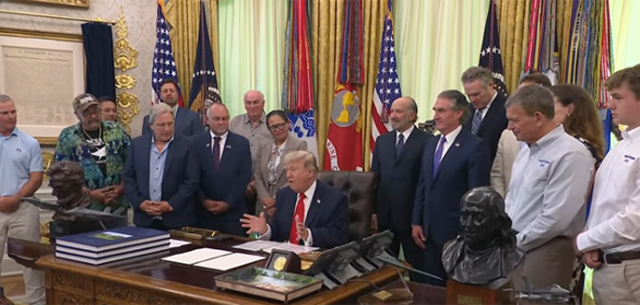 Trump in the Oval Office, surrounded by cronies.
